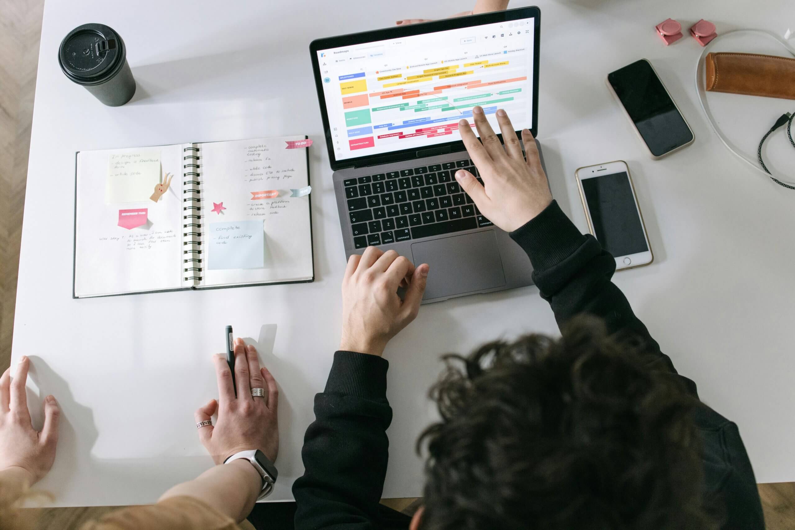 Mesa de escritorio con persona realizando tareas en su portátil